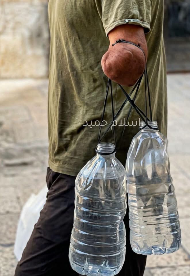 الأمرُ طبيعيٌّ.. أحدُهم يحملُ بيده قنانيَ الماء. الأمرُ غيرُ طبيعيٍّ.. أحدُهم هنا.. فلسطين…